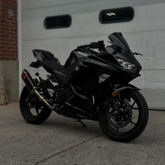 a black motorcycle parked in front of a garage