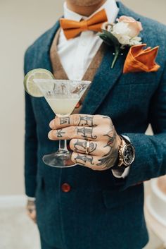 a man in a blue suit holding a martini glass with a lime slice on it