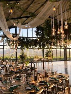 an indoor dining area with tables and chairs set up for a formal function in front of large windows