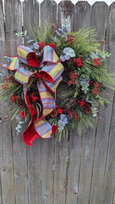 a christmas wreath hanging on the side of a wooden fence