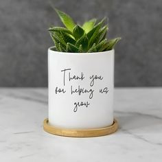 a plant in a white ceramic pot that says thank you for helping us grow