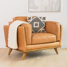 a tan leather chair with a throw pillow on it