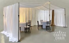 a room with white drapes and tables set up for a wedding reception at the canton chair rental center