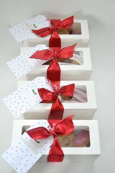 three white boxes with red bows and cookies in them on top of each other,