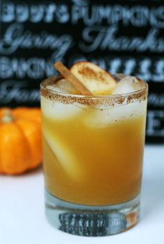 a close up of a drink in a glass with cinnamon stick garnishes