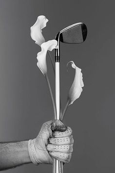 a person holding a golf club and flowers in their left hand, black and white photograph