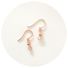 two pairs of copper earrings sitting on top of a white plate