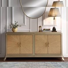 a large round mirror sitting on top of a dresser next to a lamp and table