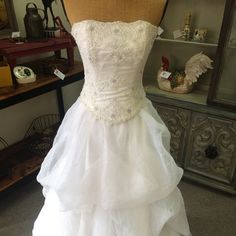 a white wedding dress is on display in a room with other items and accessories behind it