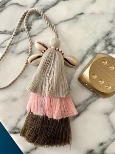 two tassels on a marble surface next to a gold object