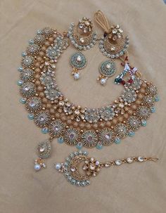 an elaborate necklace and earring set is displayed on a piece of cloth with other jewelry items