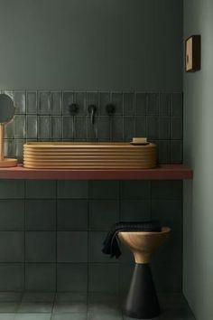 a bathroom with green walls and black tiles on the wall, along with a wooden sink