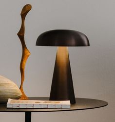 a table with a lamp and book on it, next to a statue or sculpture