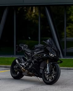 a black motorcycle parked in front of a building with large windows on it's side