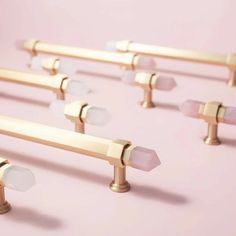 several brass handles and knobs on a pink background with white frosted glass drops