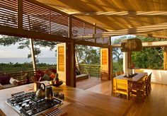 an open kitchen and dining area with wood flooring overlooking the ocean on a sunny day