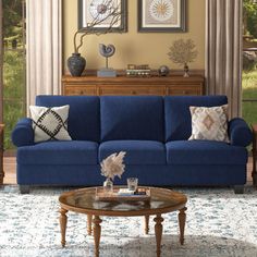 a living room with blue couches and pictures on the wall above them in front of a coffee table