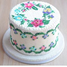 a white cake with flowers on it sitting on top of a wooden table next to a plate