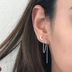 a close up of a person wearing earrings with chains hanging from it's ear