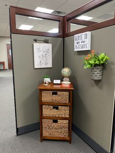 an office cubicle with two baskets and a sign on the wall next to it