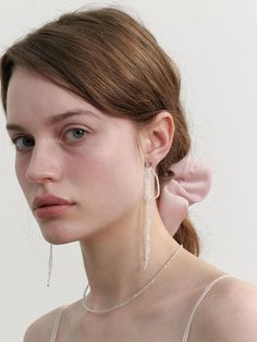 a woman wearing earrings and a pink dress