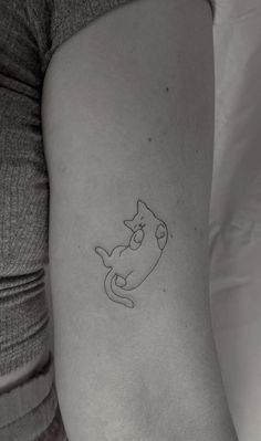 a small cat tattoo on the left inner arm and leg, with an outline of a cat