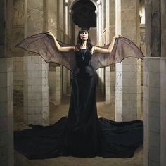 a woman in a black dress with large wings