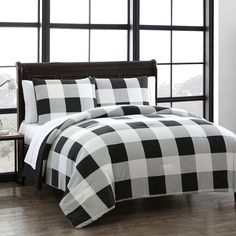 a black and white checkered comforter set on a bed in front of a window