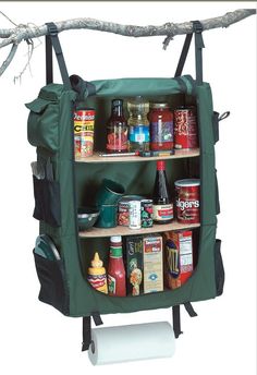 an outdoor camping shelf with spices and condiments on it, hanging from a tree branch