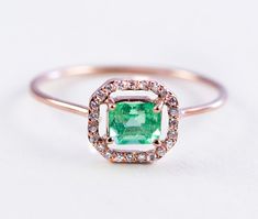 an emerald and diamond ring on a white background