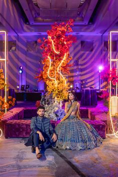 a man and woman sitting next to each other in front of an elaborate display with flowers