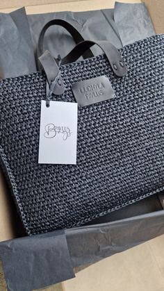 a gray and black bag sitting on top of a cardboard box with a price tag