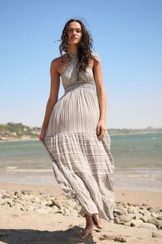 A abstract striped woven maxi dress with a halter neckline, mocked high-waist band, tiered ruffle design, and an open back. Model Info:Height: 5 ft 9.5 in | Bust: 31 in | Waist: 23 in | Hips: 33 in | Wearing Size Small Material: 100% Rayon Elegant Beach Maxi Dress With Tiered Skirt, Elegant Tiered Skirt Maxi Dress For Beach, Elegant Tiered Maxi Dress For Beach, Bohemian Tiered Maxi Dress With Tie Back, Fitted Tiered Maxi Dress For Beach, Summer Tiered Skirt Maxi Dress With Tie Back, Chic Striped Tiered Dress, Ruffled Halter Neck Sundress, Bohemian Ruffled Halter Dress For Vacation