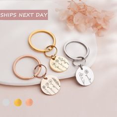 three different types of personalized key chains on a white plate with pink flowers in the background