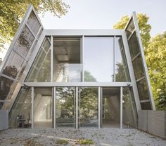 an unusual house in the middle of a park with large glass windows on it's sides