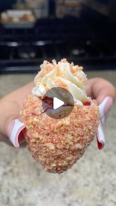 someone is holding up a cupcake with white frosting and sprinkles