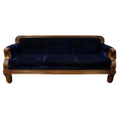 a blue velvet couch with gold trimmings on the arms and back, against a white background