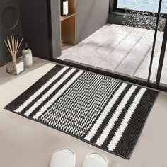 a pair of white slippers sitting on top of a bathroom floor next to a black and white rug