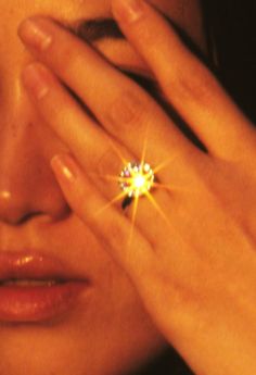 a woman holding her hand to her face with a diamond ring on it's finger