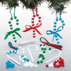 christmas decorations made out of beads and ribbon hang from a tree branch on a white background