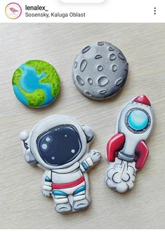 three space themed cookies sitting on top of a wooden table next to a green and blue ball