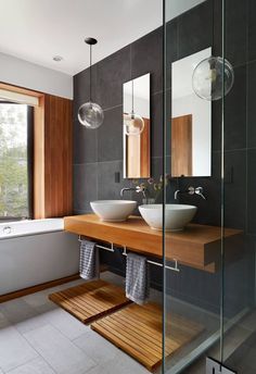 two white bowls are sitting on a wooden counter in front of a bathtub and window