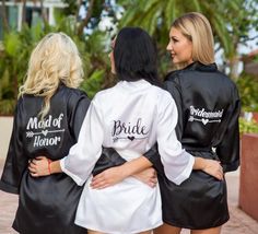 three women in black and white robes standing next to each other with their arms around one another