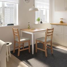 a kitchen table with two chairs and a clock on the wall in front of it