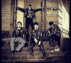 group of young men sitting on steps in front of brick building with one holding his arms out