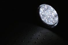 a close up of a light in the dark with water droplets on it's surface