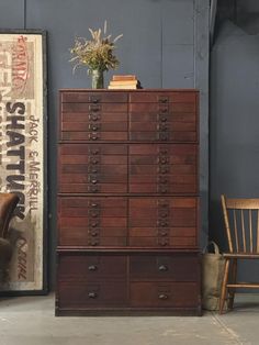 a tall wooden dresser sitting next to a chair