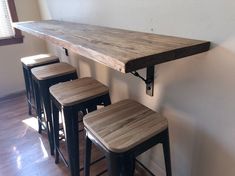 three stools and a table in the corner of a room with a window behind them