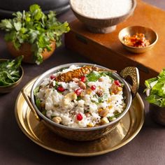 a bowl filled with rice and vegetables on top of a gold plate next to other bowls