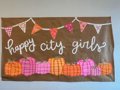 a sign that says happy city girls decorated with pumpkins and bunting on a string